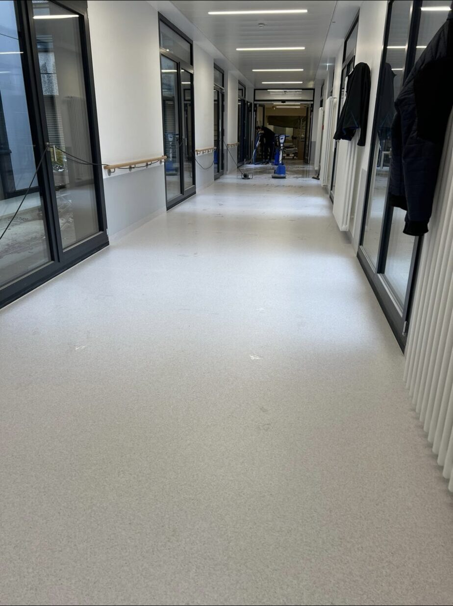 Krankenhausflur mit hellem Boden und Arbeitsgeräten im hinteren Abschnitt