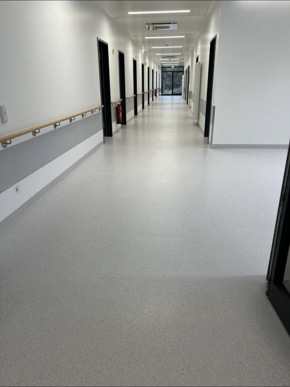 Langer Stationsflur mit freier Bodenfläche und Handläufen aus Holz