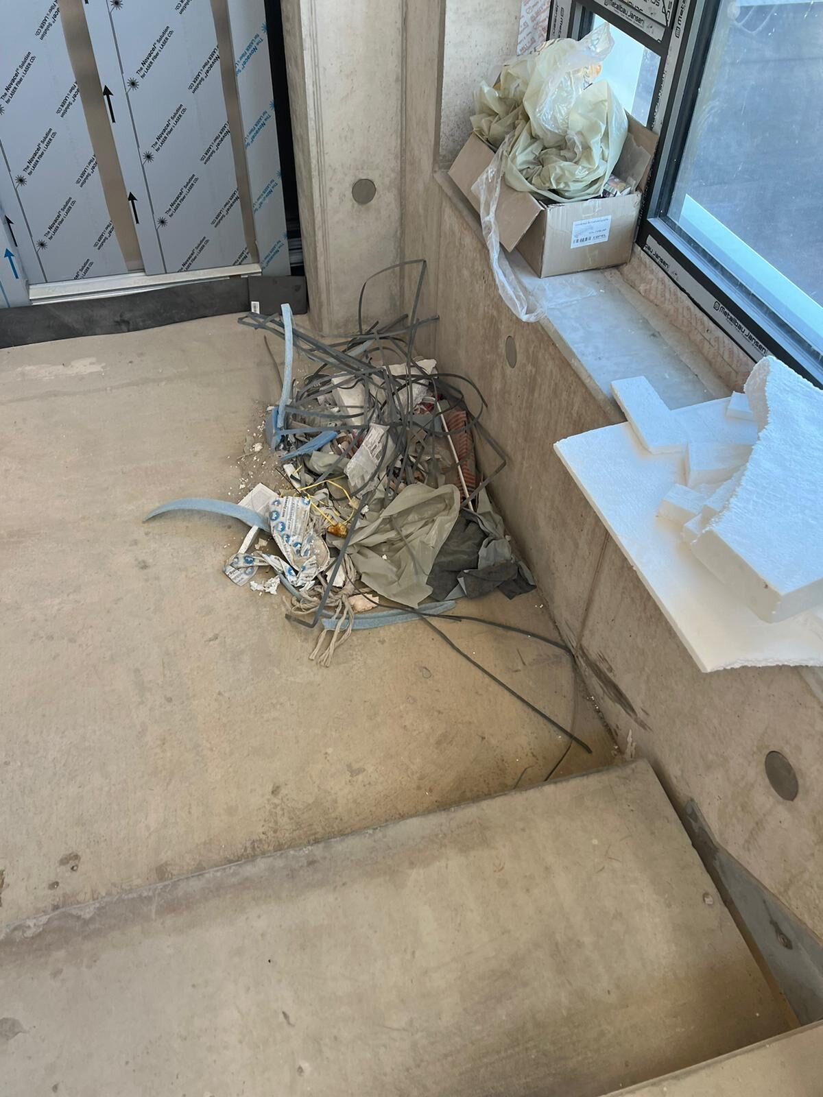 Baureste auf dem Treppenpodest und Verpackungsmaterial auf der Fensterbank