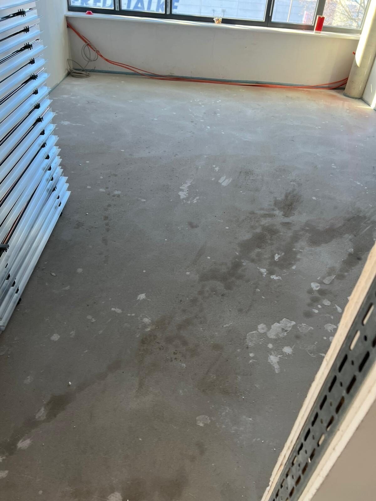 Büroraum mit gestapelten Bauteilen und weißen Rückständen auf dem Boden