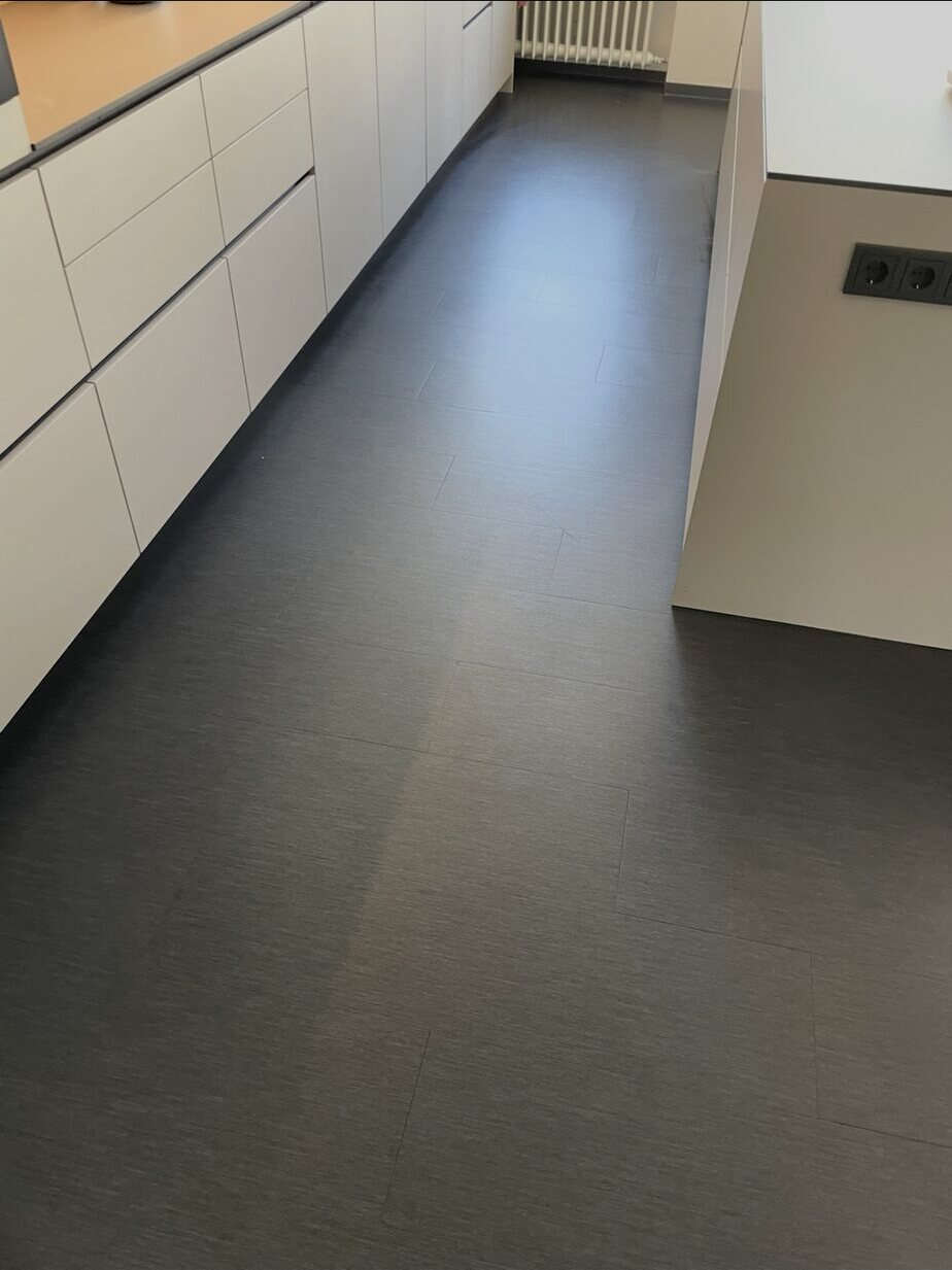 Leicht glänzender Boden im Gang zwischen Küchenzeile und Kücheninsel