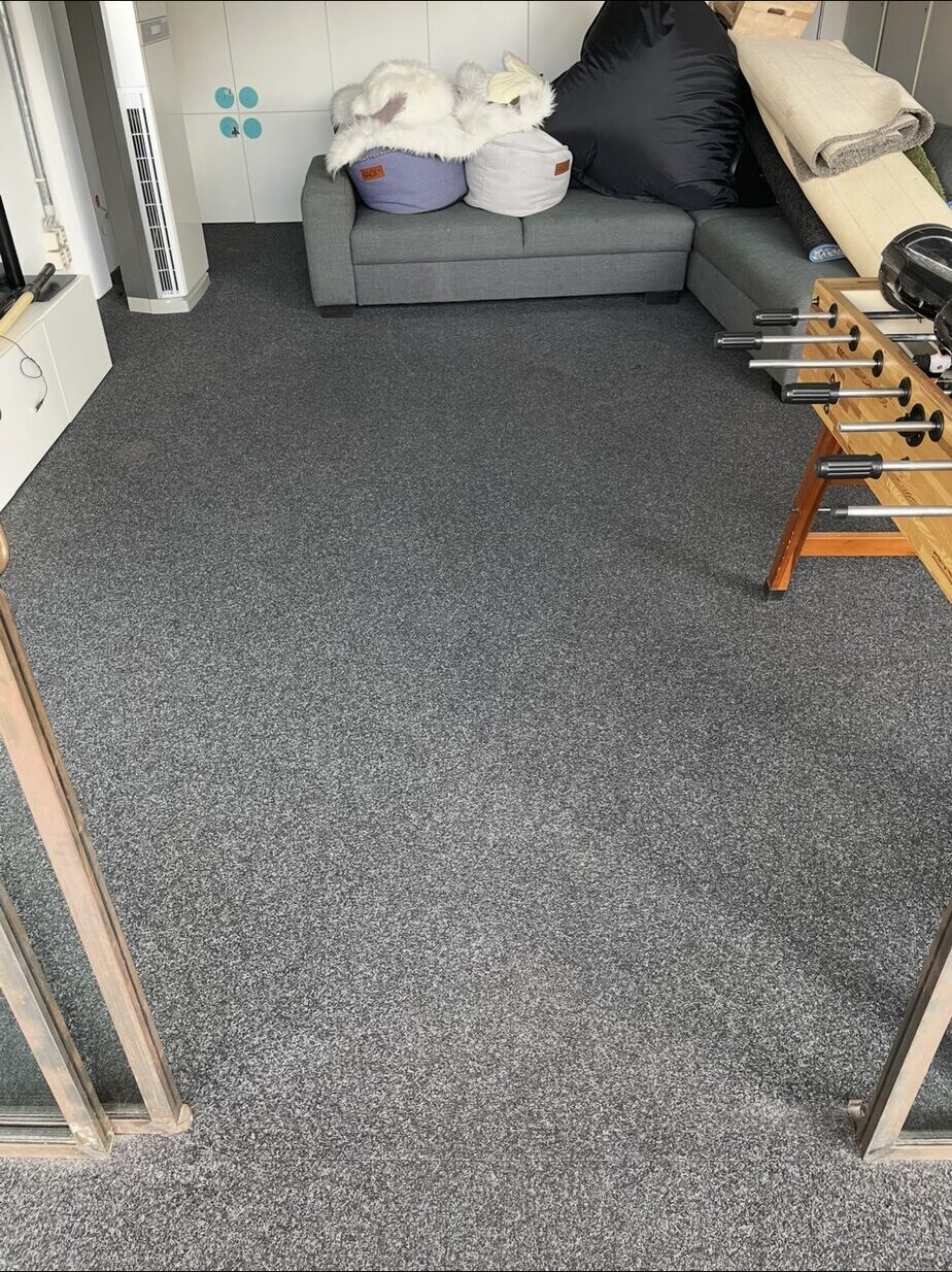 Freigeräumte Bodenfläche im Aufenthaltsraum vor Sofa und Tischkicker