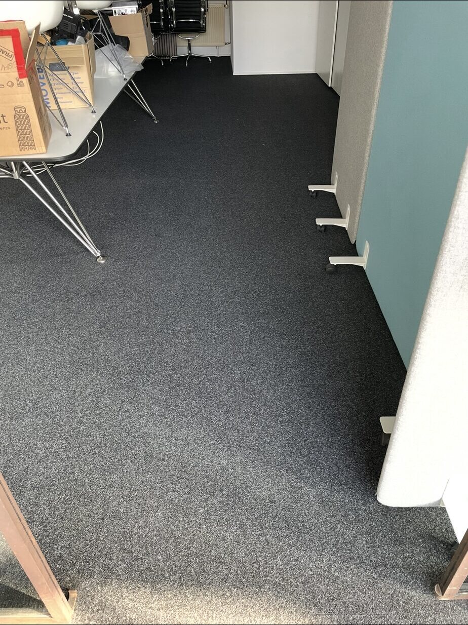 Dunkler Teppichboden mit freiem Durchgang zwischen Tischen und Stellwänden